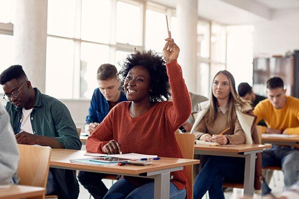 一个微笑的大学生在满教室里举手